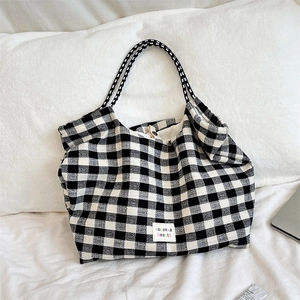Detailed view of black and white checkered tote bag with woven texture on soft bedding