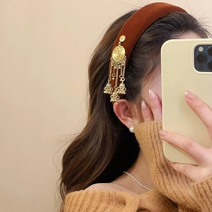 Close-up of brown velvet headband featuring ethnic golden jhumka tassel accents