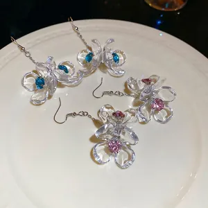 Floral acrylic drop earrings with rhinestones in pink and blue on a white ceramic plate