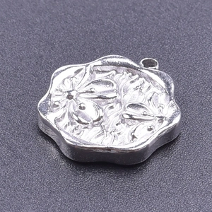 Macro shot of silver wave-edge 304 stainless steel pendant with embossed floral patterns