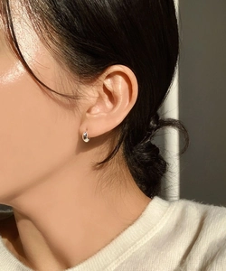 Detail view of small oval 925 silver earring worn by a model in soft natural light