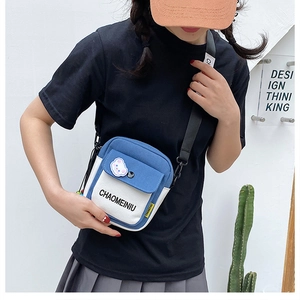 Close-up of blue canvas crossbody bag with adjustable strap shown on a model