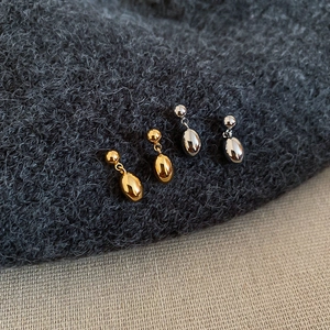 Vue macro de boucles d'oreilles en or 18 carats et argent sur un fond de pull en maille