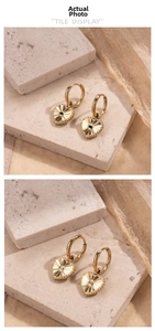 Detail von 18K Gold-Herzohrringen mit Sonnenstrahlen-Relief und zentralem Edelsteineinsatz