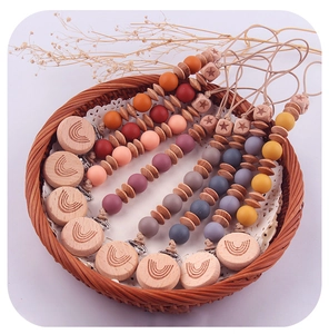 Detail of wooden beech clips with rainbow engraving and colorful silicone baby pacifier chains