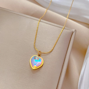 Titanium steel gold heart necklace with iridescent pendant on beige display stand