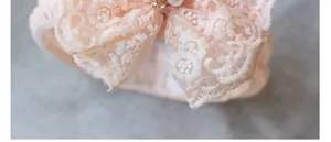 Detailed close-up of lace baby headband with embroidery, pearls and rhinestones