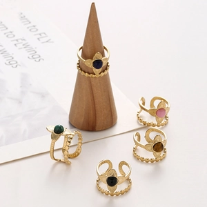 Detailed close-up of gold double-layer flower rings with colorful stones on wooden stands