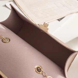 Pink crossbody bag with gold chain strap and metal clasp shown on fashion magazine