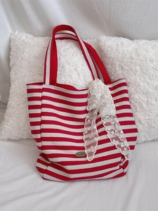 Large striped canvas tote bag with red handles and decorative white lace bow accent