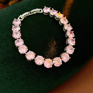 Close-up of pink round-cut cubic zirconia bracelet on dark green velvet background