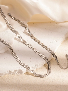 Detailed view of silver braided flat snake chain necklace on white silk and rock