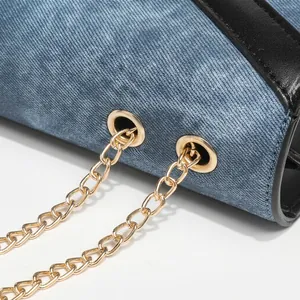 Detailed close-up of blue denim fabric with gold chain strap and black leather trim