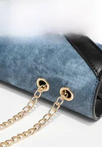 Detailed close-up of blue denim fabric with gold chain strap and black leather trim