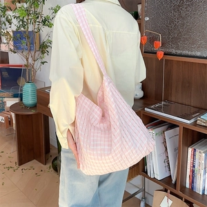 Détail d'un sac cabas en toile à carreaux roses et blancs porté à l'épaule par un mannequin