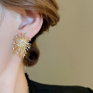 Macro shot of gold sunburst earrings featuring sparkling zircon stones on female ear