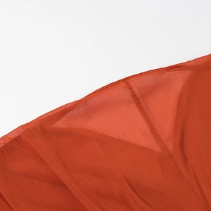 Detail of rust red pleated fabric showing fine texture and sewing of the V-neck dress