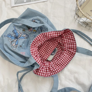 Detail of denim tote bag with bow embroidery and red gingham drawstring lining