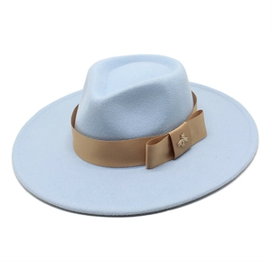 Detail of light blue wool fedora hat with camel ribbon and golden bee brooch