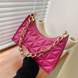 Macro view of rose pink quilted leather bag with chunky gold metal chain detail