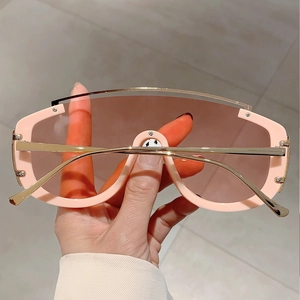 Detail of pink oversized sunglasses with gold metal top bar and brown lenses