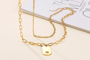 Close-up of golden double-layer necklace with a square hollow heart pendant on a magazine