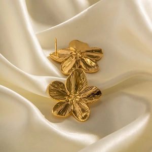 French vintage matte gold stainless steel flower earrings on white silk fabric background