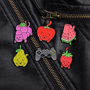 Detail of six cartoon fruit cat enamel pins on black leather jacket showing vibrant colors