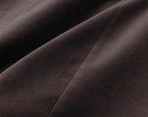 Vue macro d'un tissu en velours marron foncé montrant une texture douce et un beau drapé