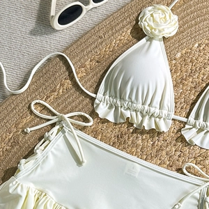 Detail of cream bikini top with 3D rose applique and ruffle edge on straw texture
