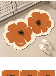 Detail of fancy orange floral bath mat with absorbent texture on stone floor