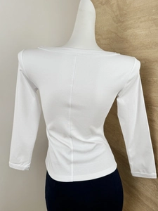 Detail of white slim fit ribbed long sleeve top showing back silhouette and fabric texture