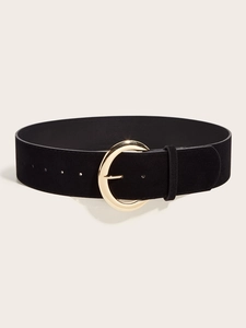 Détail d'une large ceinture en daim noir avec une grande boucle circulaire en métal doré