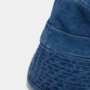 Detailed macro view of deep blue denim fabric texture and neat white stitching on bucket hat