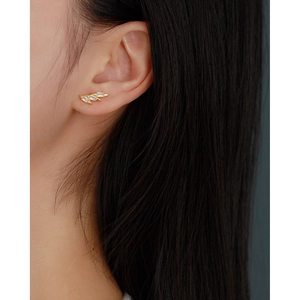 Close-up of golden stud earring with three rectangular crystals on a female model