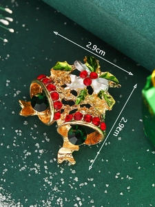 Detailed close-up of Christmas double bell brooch with red crystals and holly leaves