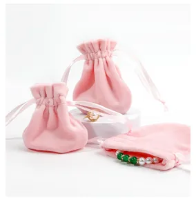 Pink velvet drawstring jewelry pouch detail with gold rings on white display stands