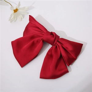 Elegant oversized dark red satin bow hair clip on a clean white background with a daisy