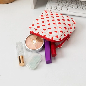 Borsa da trucco trapuntata con cuori rossi e cerniera per riporre i cosmetici su un tavolo
