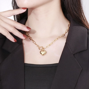 Close-up of a gold heart pendant necklace on a model with thick paperclip chain links