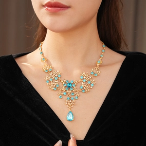 Detail of vintage gold flower pendant necklace with blue crystal water drop on model