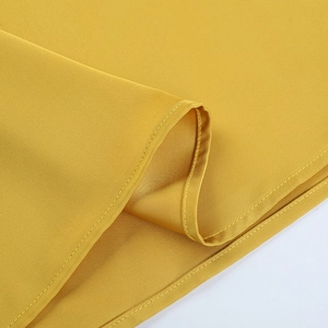 Gros plan détaillé de l'ourlet à double couture et de la texture du satin jaune vif