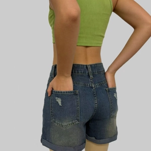 Dettaglio delle tasche posteriori sfrangiate e dell'orlo risvoltato degli shorts