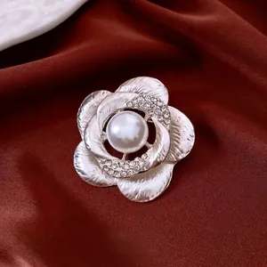 Elegant floral pearl brooch with diamonds and brushed metal finish on burgundy silk