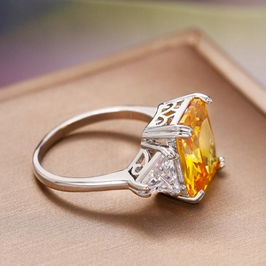 Anillo elegante con citrino amarillo rectangular y piedras laterales en banda plata