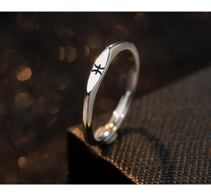 Macro detail of S925 silver Pisces zodiac ring with polished finish on black texture