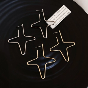 Macro detail of geometric star stud earrings in gold and silver on a black tray