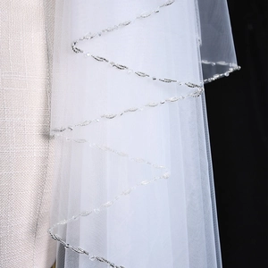 Detail of bridal veil with wavy silver beadwork and sequins on white tulle fabric