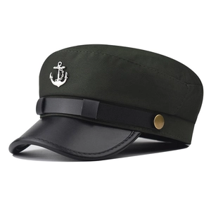 Detail of silver anchor emblem and leather strap on olive green sailor cap