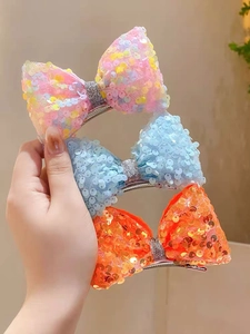 Detail of sequined mermaid bow hair clips in pink, light blue, and bright orange colors